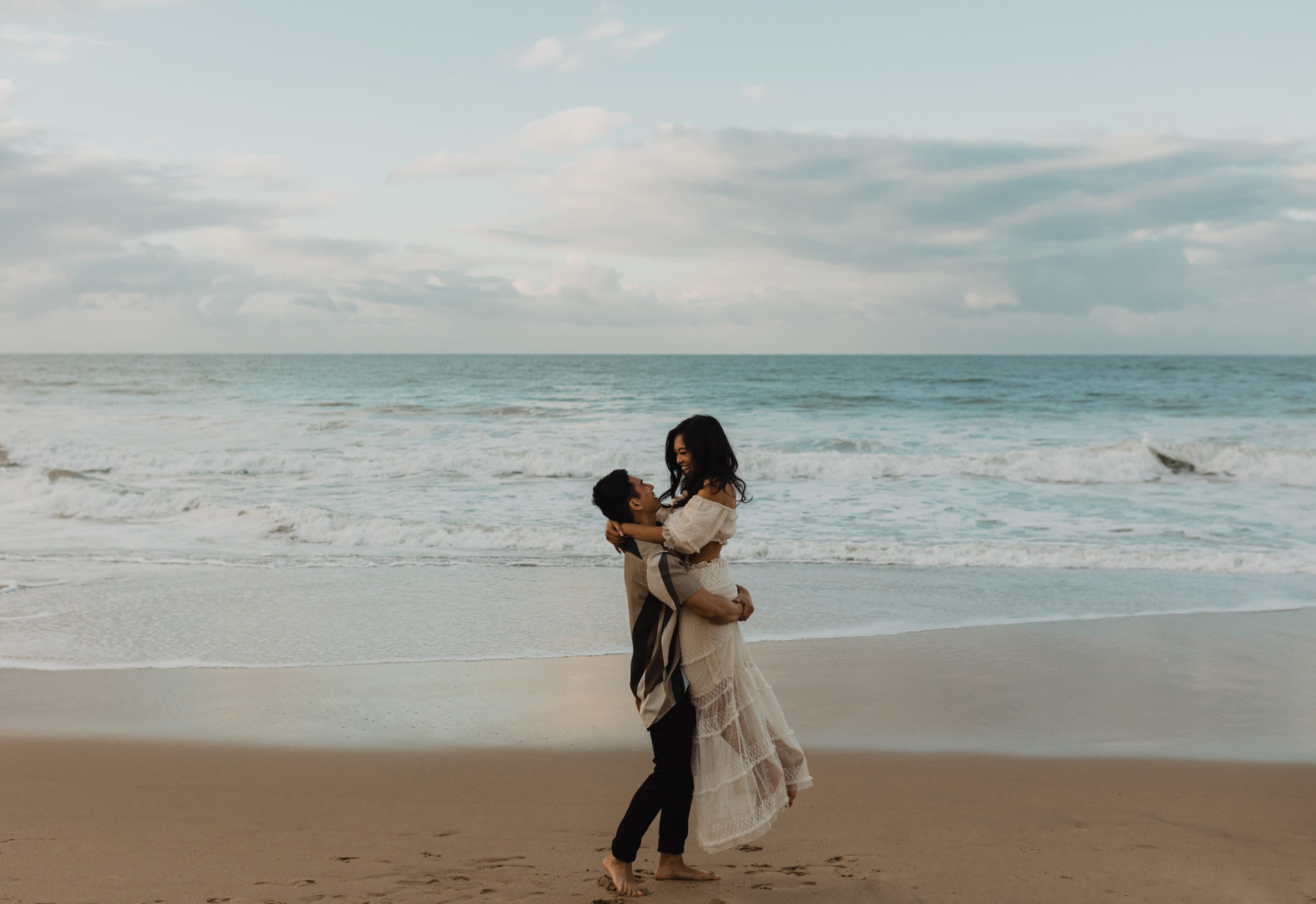 engaged couple embraces on a beach at crystal cove near laguna beach california