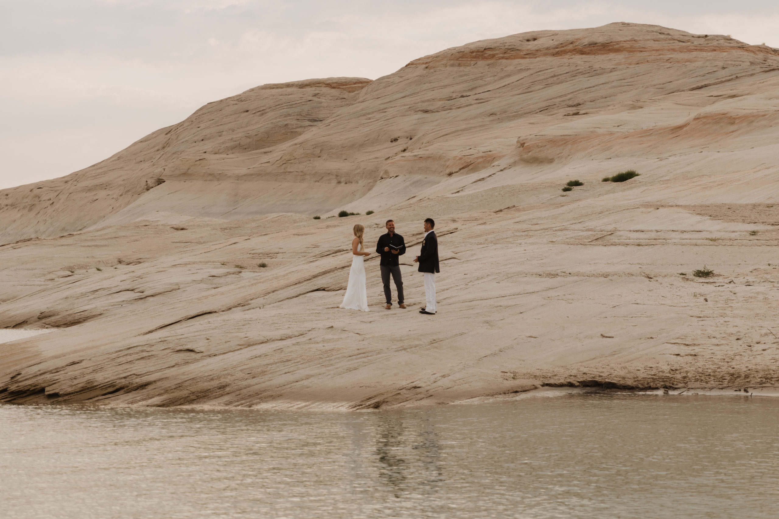 Couple and officiant in an elopement ceremony on the shores of Lake Powell in Utah