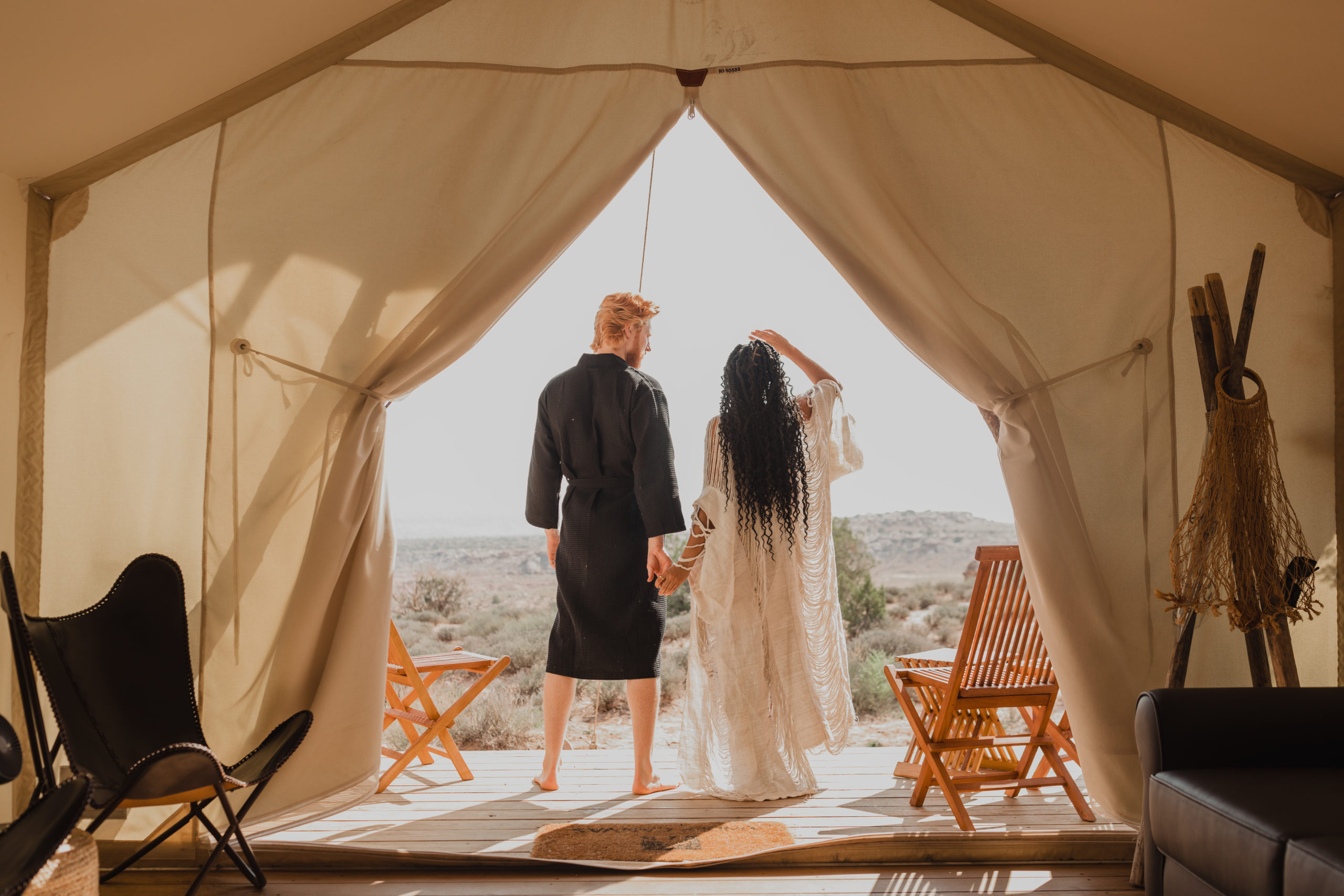 Bride and groom stand in the doorway of their glamping tent at Under Canvas Moab