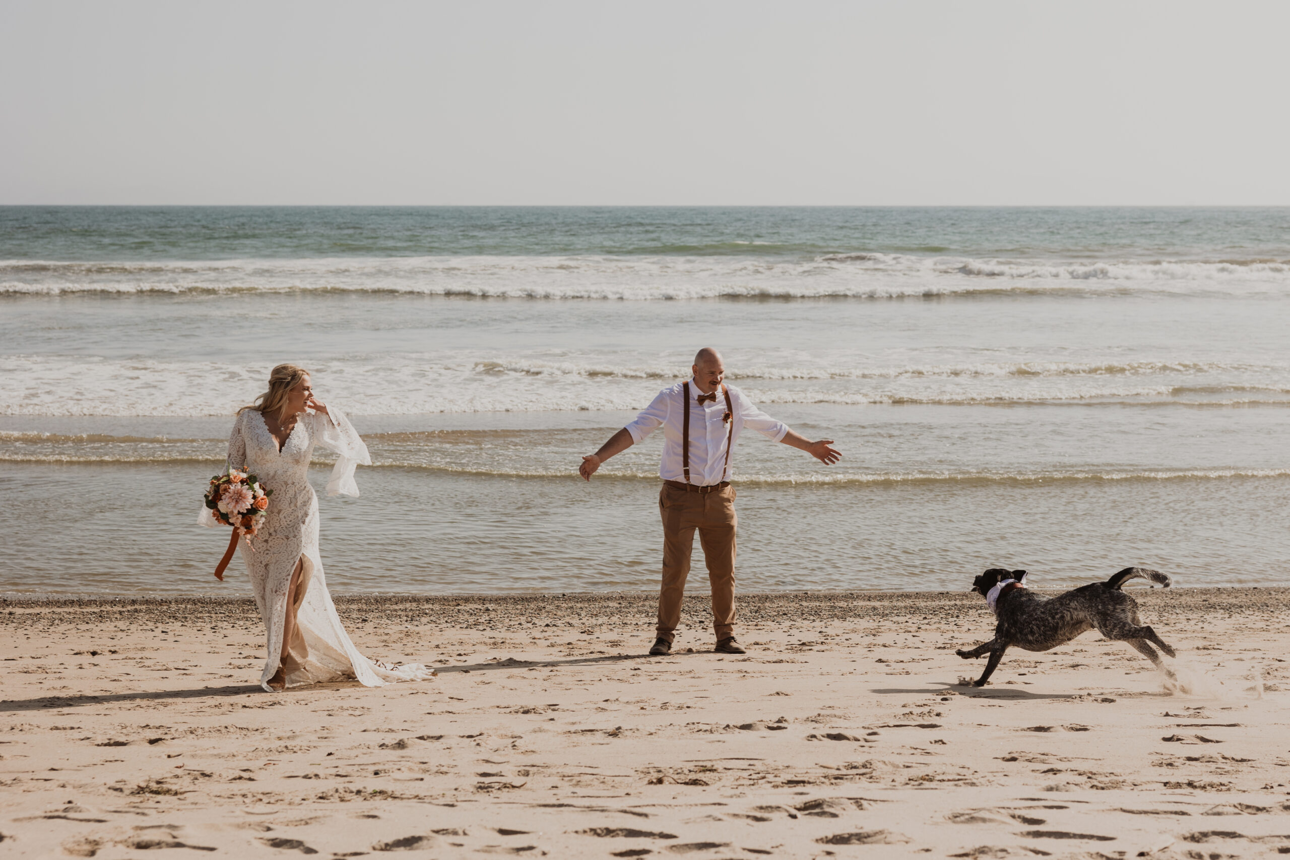 Bride and groom walk on the beach with their dogs after an intimate beach wedding in Los Angeles